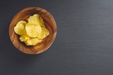 Siyah arka planda, üstten görünüm, kase gevrek patates cipsi alanı Kopyala