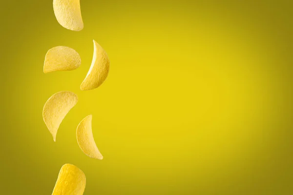 Falling potato chips isolated on yellow background. Flying crispy snacks — Stock Photo, Image