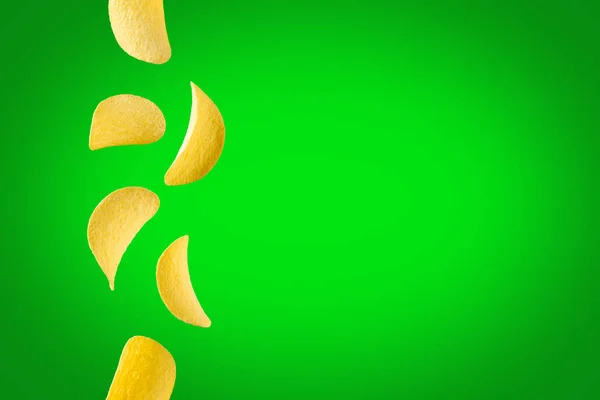 Falling potato chips isolated on green background. Flying crispy snacks — Stockfoto