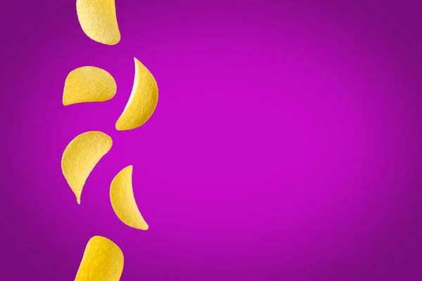 Falling potato chips isolated on purple background. Flying crispy snacks — Stock Photo, Image