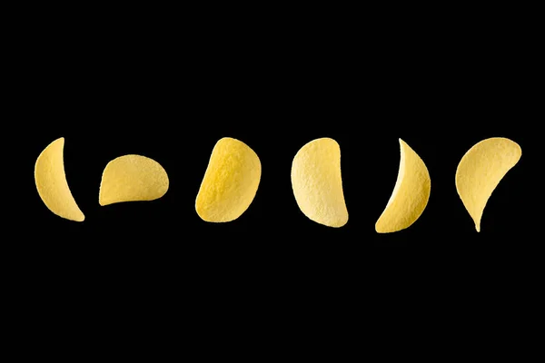 Fallende Kartoffelchips isoliert auf schwarzem Hintergrund. Schweben knusprige Snacks lizenzfreie Stockfotos
