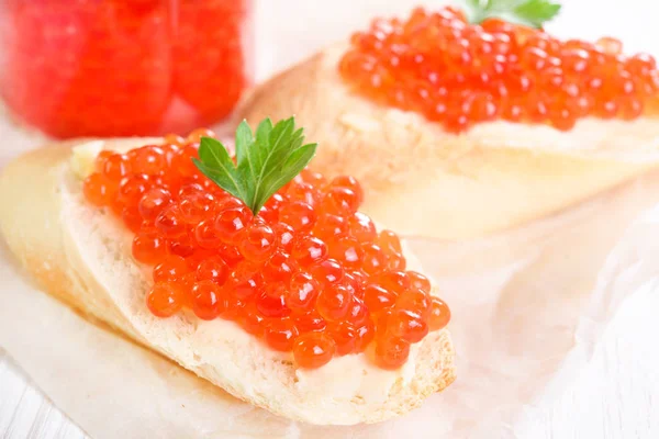 Snacks mit rotem Kaviar auf weißem Papier in Großaufnahme Stockfoto