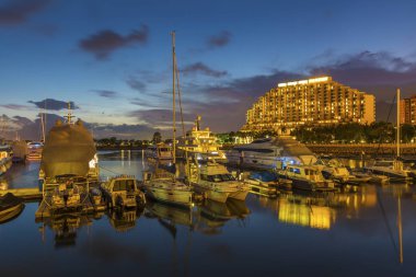 Limandaki yat ve motorlu tekne Hong Kong 'da gün batımında iskeleye demirlemiş.