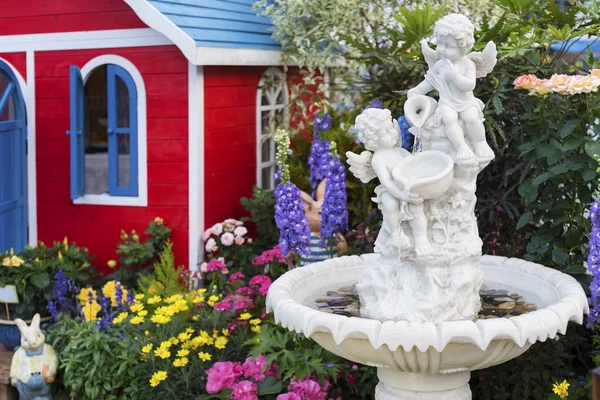 Fountain and sculpture of cherub in backyard flower garden