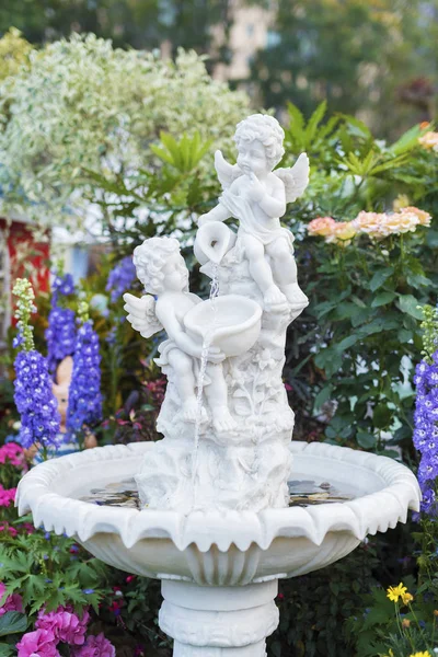 Fontana e scultura di cherubino nel giardino fiorito del cortile — Foto Stock