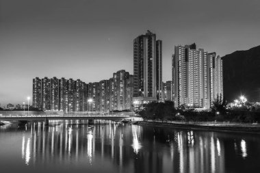 Alacakaranlıkta Hong Kong şehrinde yüksek binalar ve dağlar.