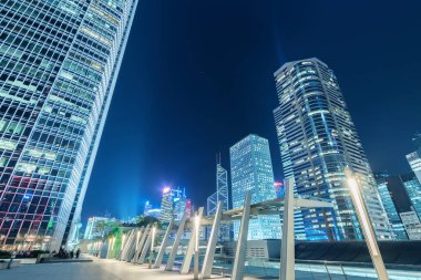 Yüksek katlı ofis binası ve geceleri Hong Kong şehir merkezindeki kamu parkı.