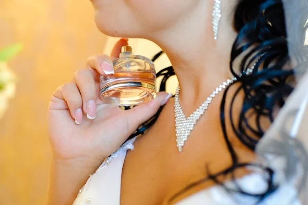 新娘的晨会 新娘穿着一件漂亮的白色礼服 脖子上有一条深的装饰和项链 女孩洒香水 — 图库照片