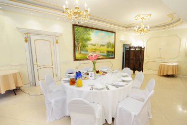 Moskova 7 Temmuz 2013: Sofra Konuklar için düğün. Parlak hall, beyaz masa örtüsü, sandalye üzerinde beyaz kapsar. Atıştırmalıklar, çatal bıçak takımı, kadehlerin, çiçekler ve masanın üzerine peçete.