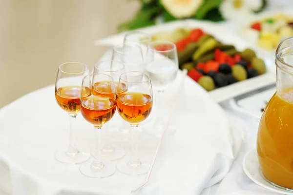 Glasses with alcoholic drink stand on the white tray on the table. Welcome drink.