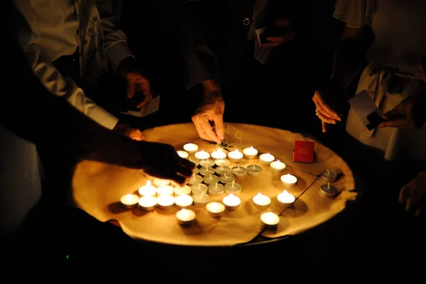 People light small candles standing on a tray. Light candles in the dark.