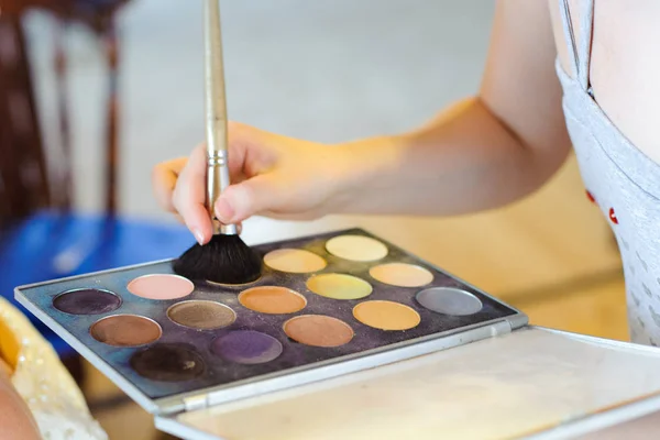 Professional pallet of eyeshadow and brush. Multicoloured eye shadows. Professional stylist makes make-up.