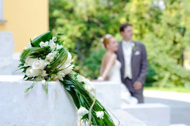 Güzel düğün buketi ve arka planda yeni evliler.