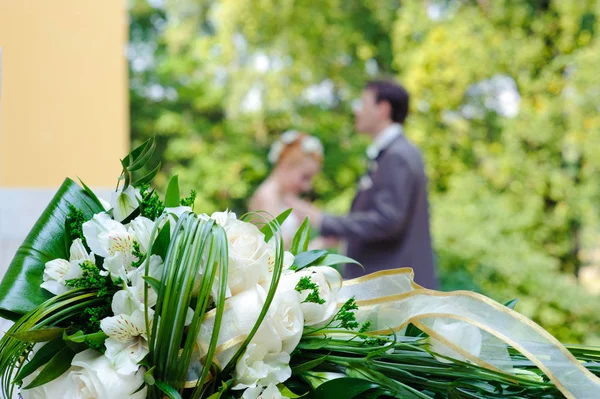 美丽的婚礼花束和新婚夫妇的背景 — 图库照片