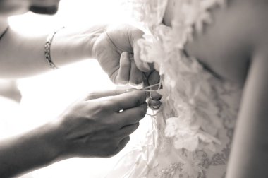 Sabah gelin hazırlanması. Kadınların elleri bir gelinlik korse üzerinde bir kurdele bağla. Siyah ve beyaz.