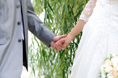 Gelin ve damat parkta yürürken el ele tutuşuyorlar. Yazın düğün günü.