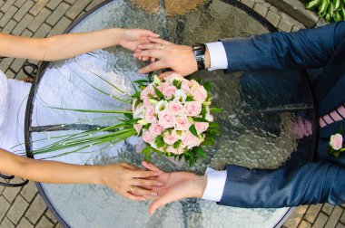 Gelin ve damat elele tutuşun. Cama gelin buketi tablodur. Düğün günü yaz aylarında.