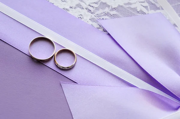 Весільні Кільця Фіолетовій Стрічці Тлі Білої Тканини Мереживом Геометричний Візерунок — стокове фото