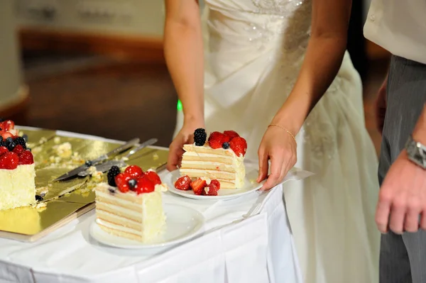 新婚夫妇切了一块用新鲜浆果装饰的婚礼蛋糕 — 图库照片