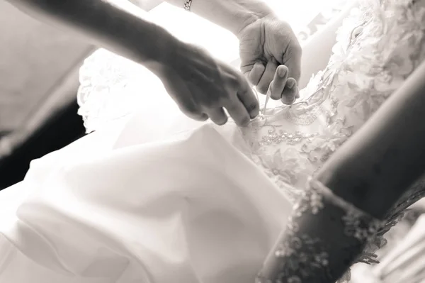 朝の花嫁の支度 女性の手は ウェディング ドレスのコルセットにリボンを結ぶ 黒と白 — ストック写真