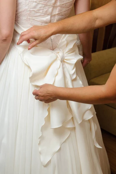 新娘的晨练 女人的手在婚纱上系上丝带上的蝴蝶结 — 图库照片