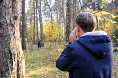 Moscow region, Rusya Federasyonu. Genç bir adam onun ile kız arıyor eller alın ağzını için. Sonbahar günü bir çam ormanı içinde. Güzel sarı ağaçlar yaktı.