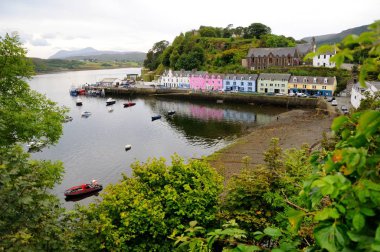 Portree liman renkli evleri ve tekneler Bay, ağaçlar ön planda. Isle of Skye, İskoçya.