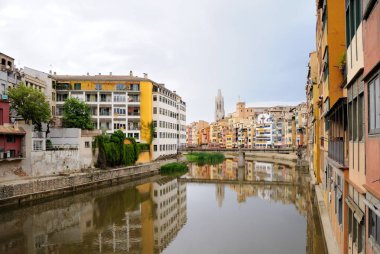 Renkli evleri, Onyar Nehri'nin suya yansıyan. Kırmızı demir köprü veya Girona Eiffel Köprüsü (Pont de les Peixateries velles) görüntüleyin. Girona, İspanya tarihi Yahudi mahallesinde.
