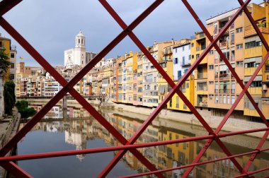 Renkli evleri, Onyar Nehri'nin suya yansıyan. Kırmızı demir köprü veya Girona Eiffel Köprüsü (Pont de les Peixateries velles) görüntüleyin. Girona, İspanya tarihi Yahudi mahallesinde.