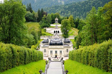 Linderhof Palace, park ve şelale çağlayan. Arka planda dağlar.