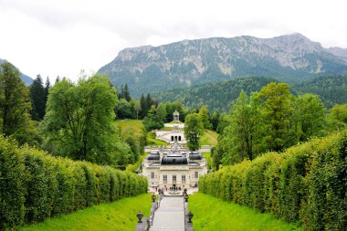 Linderhof Palace, park ve şelale çağlayan. Arka planda dağlar.