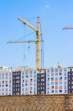 Vinçler bina ve bina yapım aşamasında çitin arkasında. Dikey kompozisyon