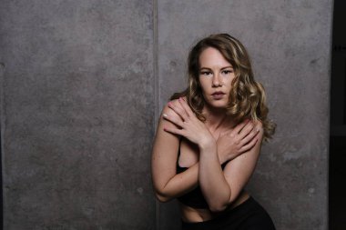 Siyah top yaslanmış ve omuzlarını gösterilen bir muhteşem sarışın manken