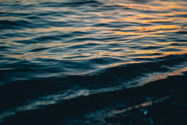 Morska biała piana na grzbiecie fali. Woda z bąbelkami. Fala spływa na brzeg. Fale morskie o świcie. — Zdjęcie stockowe
