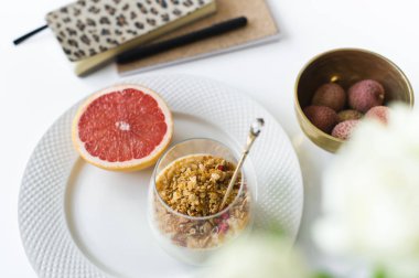 Sağlıklı kahvaltı. Malzemeler: greyfurt, granül, çay, lychee. Vazo gül. Yan bakış, beyaz arka plan.