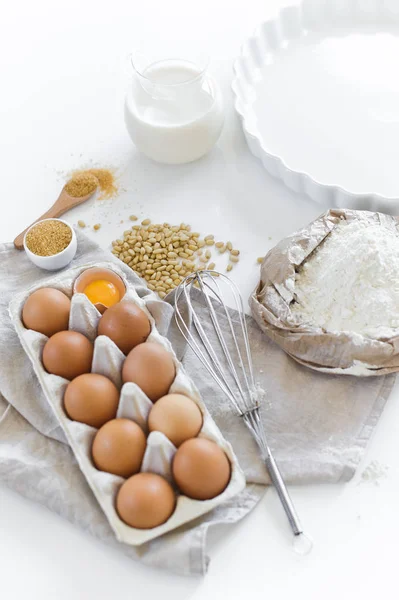 Ingredients for homemade baking. Eggs, milk, flour, sugar. White background, side view