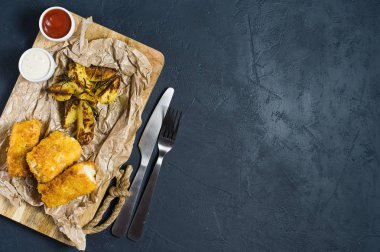 Ahşap Doğrama tahtası üzerinde İngilizce geleneksel balık ve cips. Koyu arka plan, üstten görünüm, metin için yer