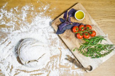 Çeşitler için malzemeler: hamur, domates, biberiye, kekik, fesleğen, zeytinyağı ahşap bir masa üzerinde. Üstten görünüm, ahşap arka plan