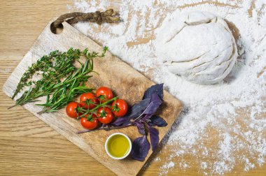 Çeşitler için malzemeler: hamur, domates, biberiye, kekik, fesleğen, zeytinyağı ahşap bir masa üzerinde. Üstten görünüm, ahşap arka plan