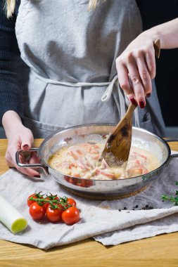 Şef biber, kırmızı biber, pırasa ve bir tavada domates sos hazırlar. Arka plan mutfak, yan görünüm