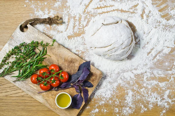 Çeşitler için malzemeler: hamur, domates, biberiye, kekik, fesleğen, zeytinyağı ahşap bir masa üzerinde. Üstten görünüm, ahşap arka plan