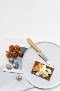 Tost bıldırcın yumurtası. Malzemeler domates, yumurta, peynir, çavdar ekmeği. Beyaz arka plan, üstten görünüm, metin için yer