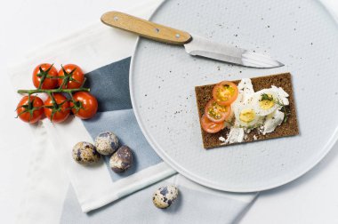 Tost bıldırcın yumurtası. Malzemeler domates, yumurta, peynir, çavdar ekmeği. Beyaz arka plan, yan görünüm