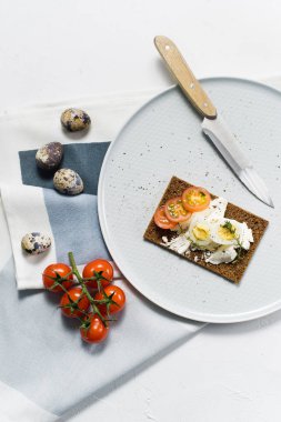 Tost bıldırcın yumurtası. Malzemeler domates, yumurta, peynir, çavdar ekmeği. Beyaz arka plan, üstten görünüm
