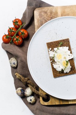Tost bıldırcın yumurtası. Malzemeler domates, yumurta, peynir, çavdar ekmeği. Beyaz arka plan, üstten görünüm