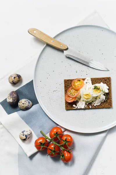 Quail egg toast. Ingredients tomatoes, egg, cheese, rye bread. White background, top view