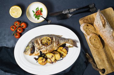 Beyaz bir plaka üzerinde ızgara Dorado balık patates kızartması garnitür. Koyu arka plan, üstten görünüm