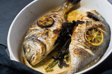 Dorado bir dilim limon ile balık pişmiş. Koyu arka plan, üstten görünüm, yakın çekim