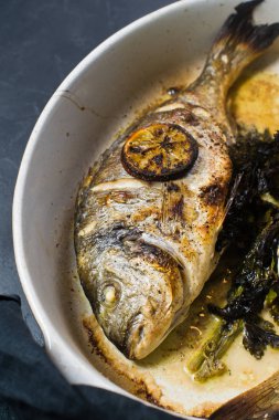 Dorado bir dilim limon ile balık pişmiş. Koyu arka plan, üstten görünüm, yakın çekim