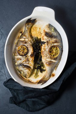 Dorado bir dilim limon ile balık pişmiş. Koyu arka plan, üstten görünüm